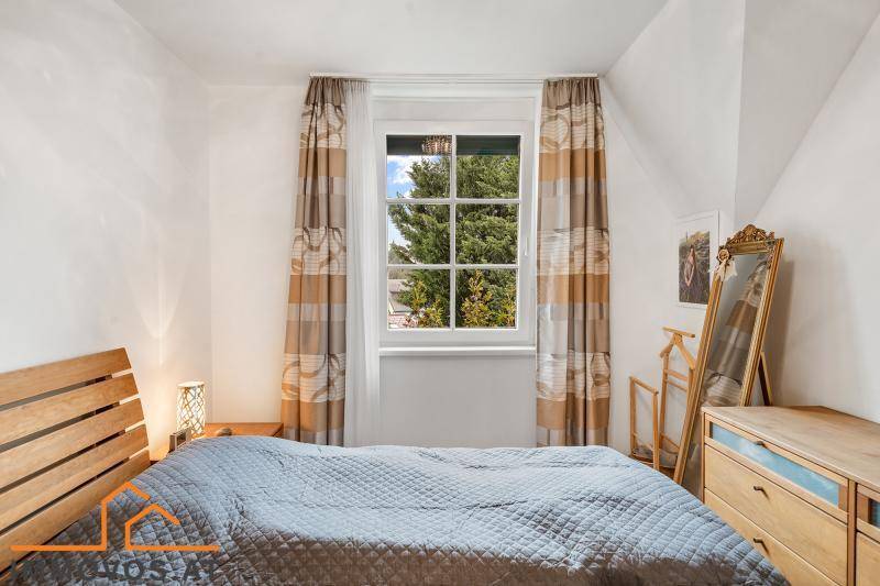 Gemütliches Schlafzimmer mit Holzbett, Holzboden und Fenster mit Blick ins Grüne.