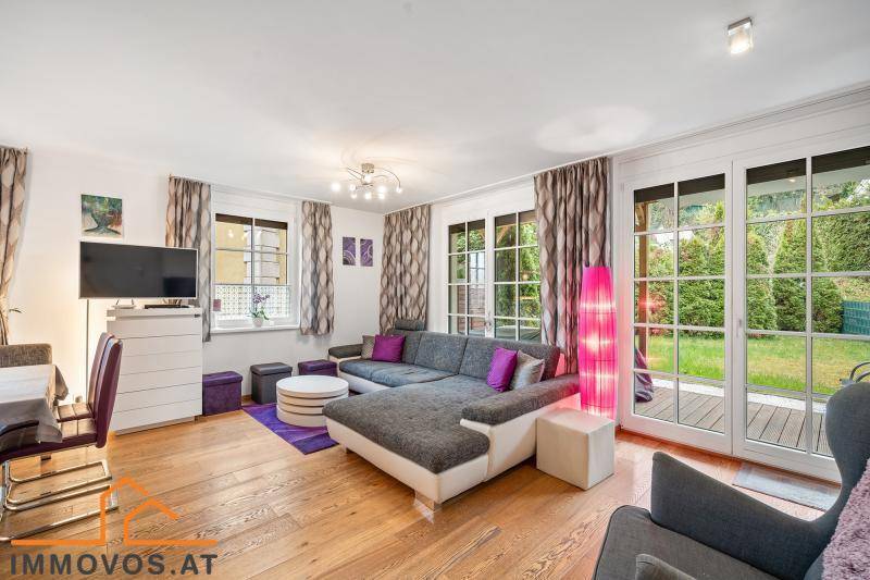 Geräumiges Wohnzimmer mit großem Sofa, Holzboden und direktem Zugang zum Garten.