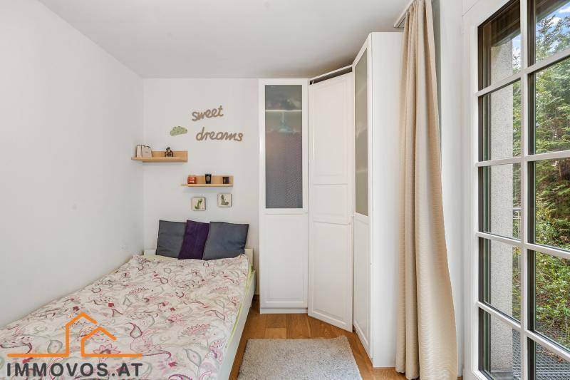 Helles Kinderzimmer mit Einzelbett, Holzboden und großem Fenster zum Garten.