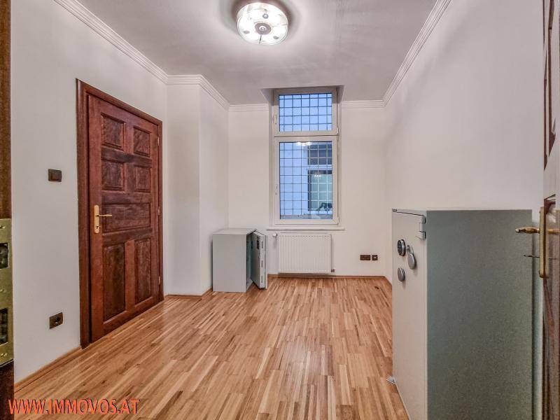 Helles Zimmer mit Parkettboden, Fenster und zwei Tresoren.