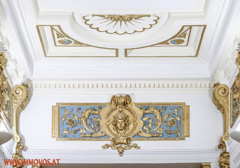 Detailaufnahme einer opulenten Stuckdecke und Wanddekoration mit goldenen Akzenten.