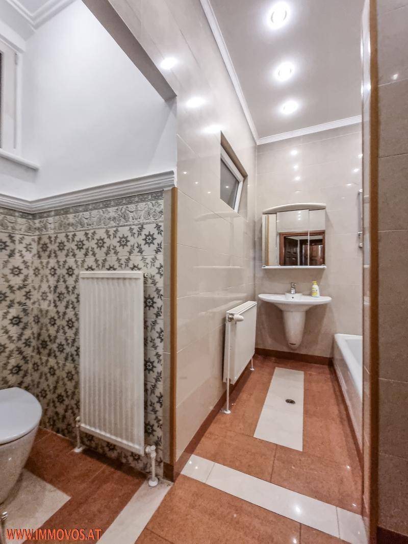 Badezimmer mit WC, Waschbecken, Badewanne und Fenster für Tageslicht.