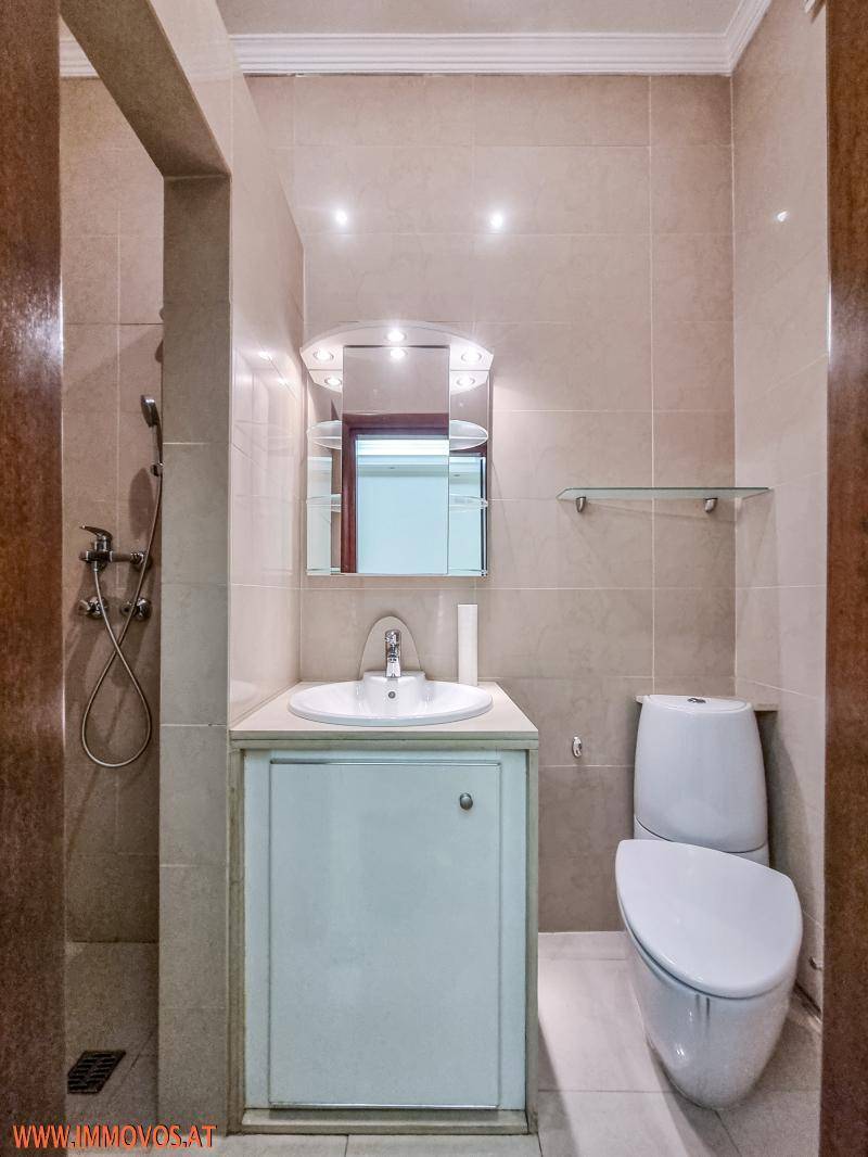 Kleines Badezimmer mit WC, Waschbecken und Duschbereich.