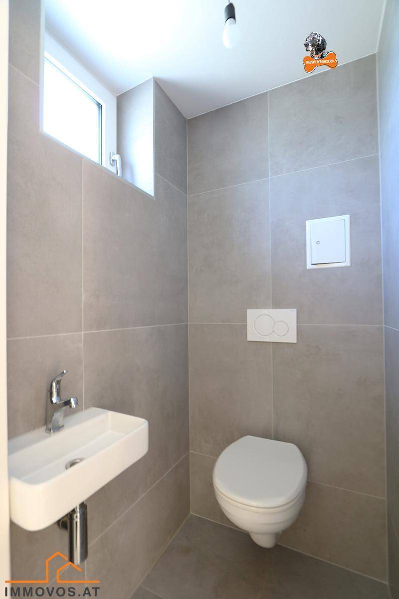 Kleines Gäste-WC mit modernen grauen Fliesen, wandhängendem WC und Handwaschbecken.