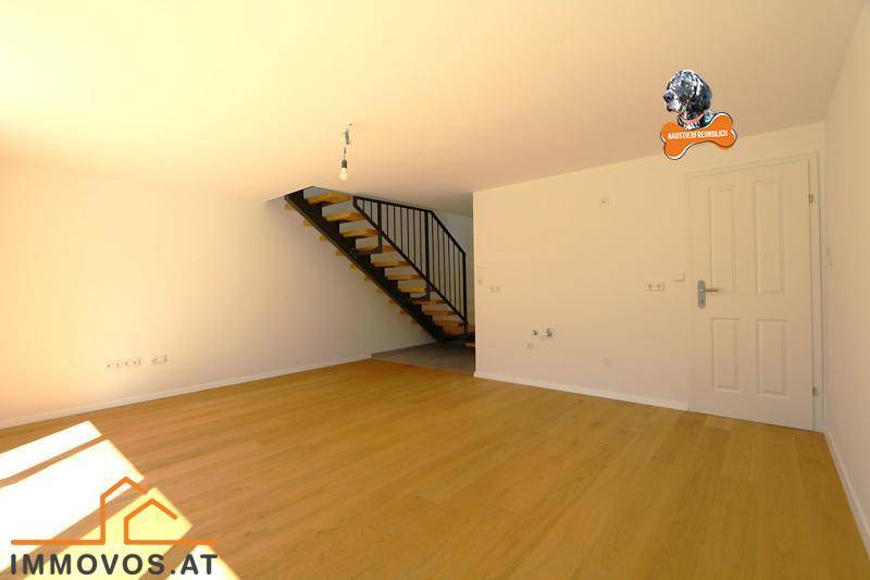 Geräumiger, heller Wohnbereich mit Holzboden und offener Treppe zum Obergeschoss.