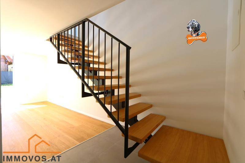 Moderne Holztreppe mit schwarzem Geländer, die die Stockwerke miteinander verbindet.