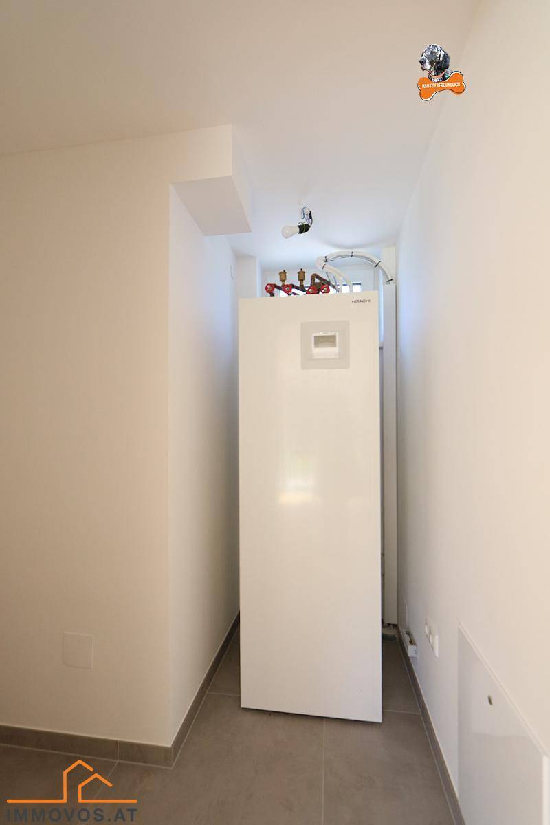 Schmaler Hauswirtschaftsraum mit großem Heizsystem und Fliesenboden.