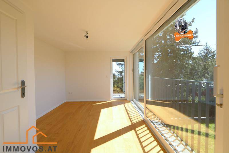 Helles Zimmer mit Holzboden und Zugang zu einem Balkon, bietet viel Tageslicht.