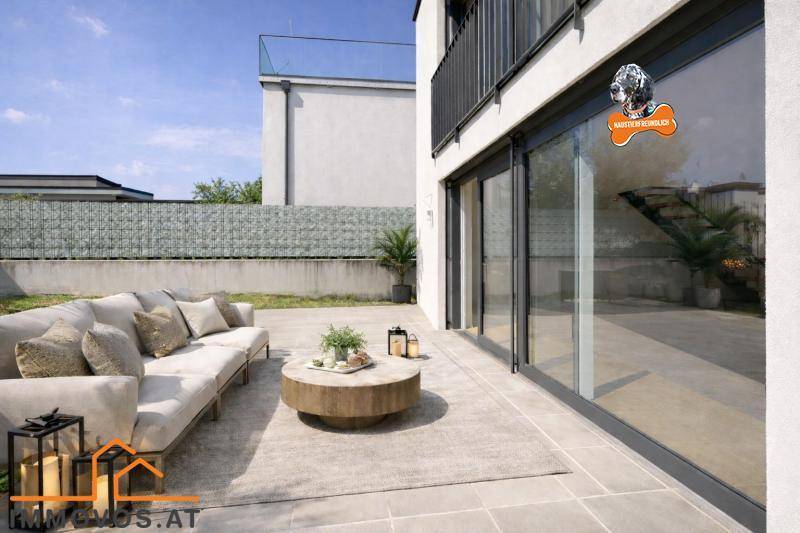 Gemütliche Terrasse mit modernen Gartenmöbeln und großen Glasschiebetüren zum Innenbereich.