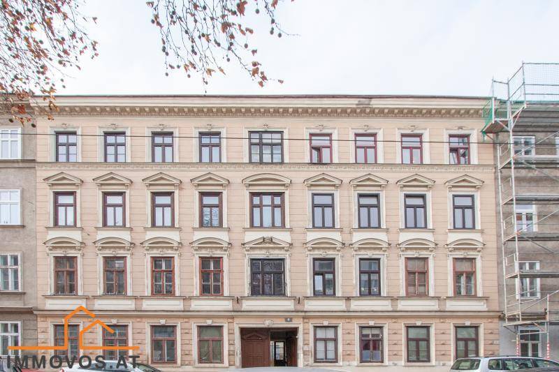 Klassische Fassade eines Altbaus mit vielen Fenstern und Gerüst an der rechten Seite.
