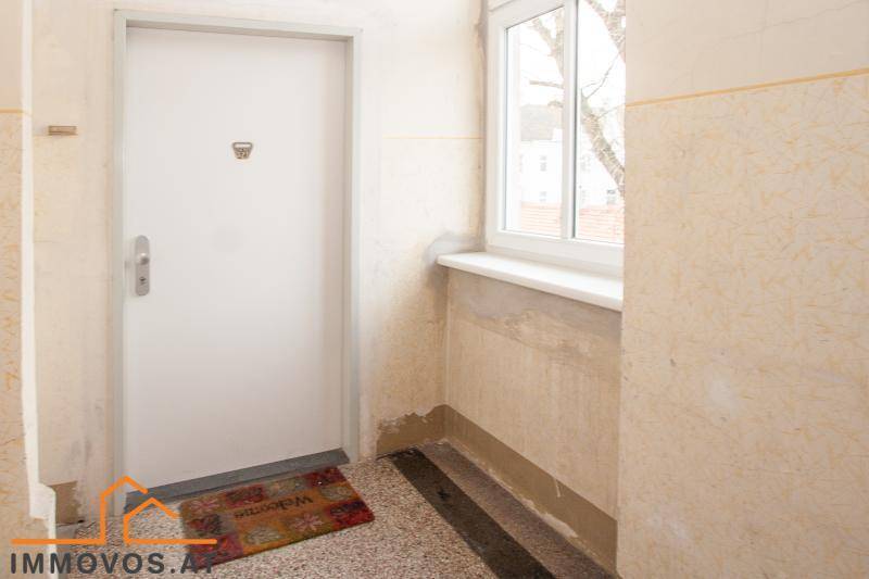 Eingangsbereich mit Haustür, Fenster und Terrazzoboden, in einem älteren, aber gepflegten Zustand.