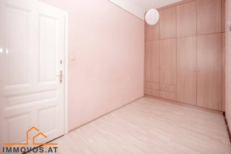 Schlafzimmer mit rosa Wänden, hellem Holzboden und praktischen Einbauschränken für Stauraum.