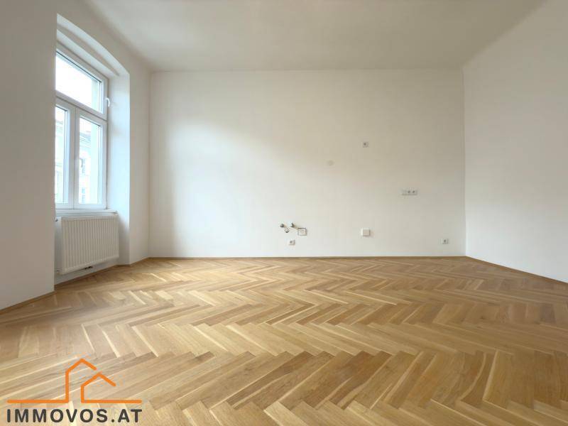 Helles, leeres Zimmer mit Fischgrätparkett und einem großen Fenster, bereit zur individuellen Gestaltung.