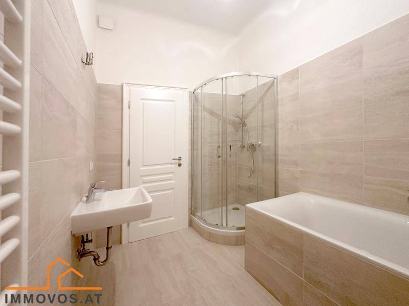Modernes Badezimmer mit Badewanne, Duschkabine, Einzelwaschbecken und beheiztem Handtuchhalter.