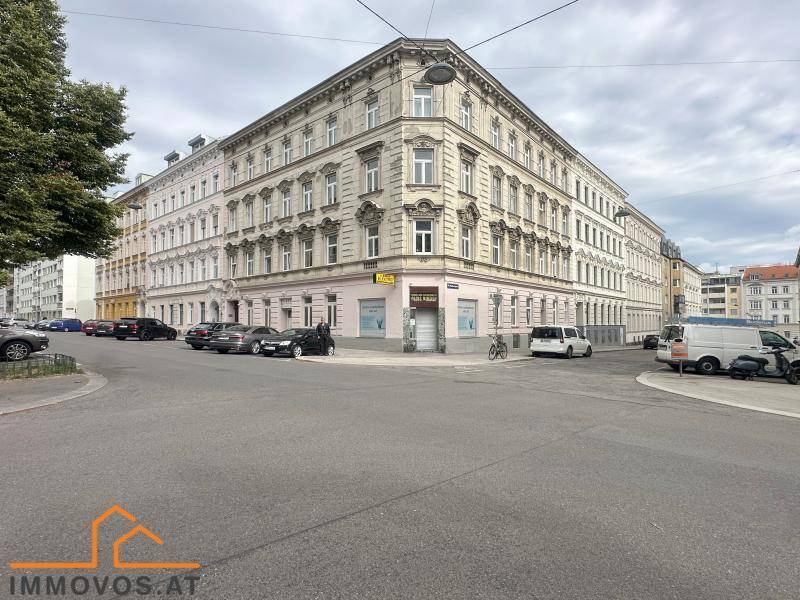 Historisches Eckgebäude in städtischer Umgebung mit klassischer Architektur und vielen Fenstern.