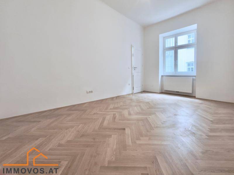 Leeres Zimmer mit hellem Fischgrätparkett und einem hohen Fenster, ideal für individuelle Nutzung.