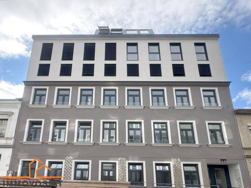 Moderne Gebäudefassade mit zahlreichen Fenstern und einer Kombination aus hellen und dunklen Grautönen.