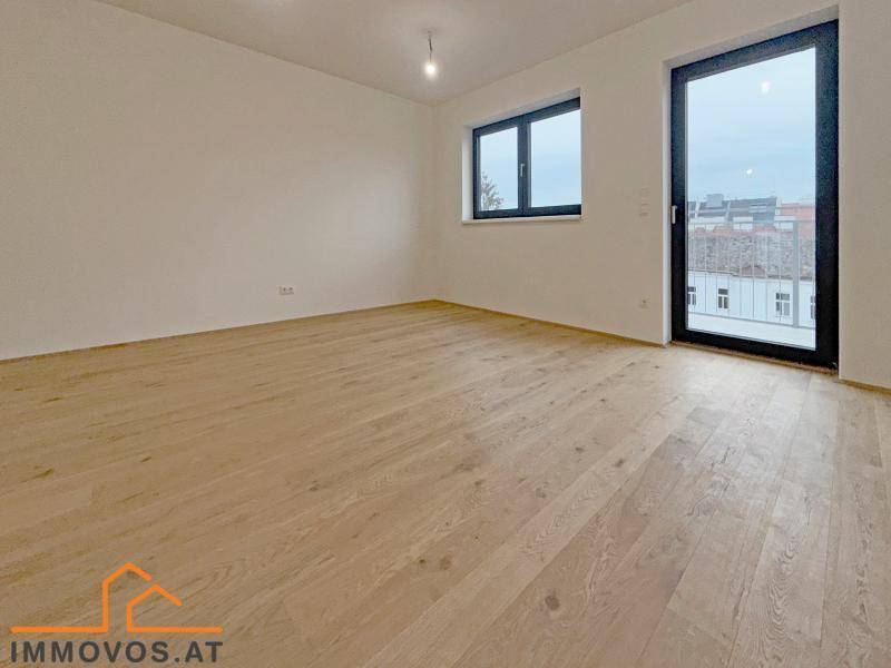 Heller, leerer Wohnraum mit Holzboden und Zugang zu einem potenziellen Balkon oder Terrasse.