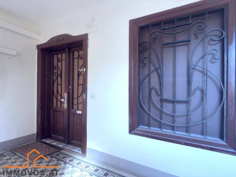 Historischer Eingangsbereich mit kunstvollen Holztüren, Fenstergittern und gemustertem Fliesenboden.