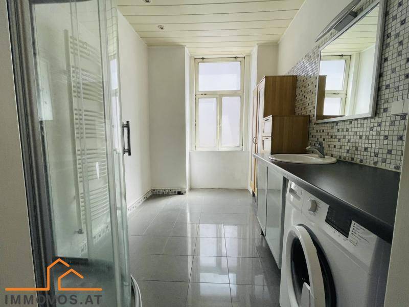 Modernes Badezimmer mit Duschkabine, Waschmaschine und Fenster für Tageslicht.