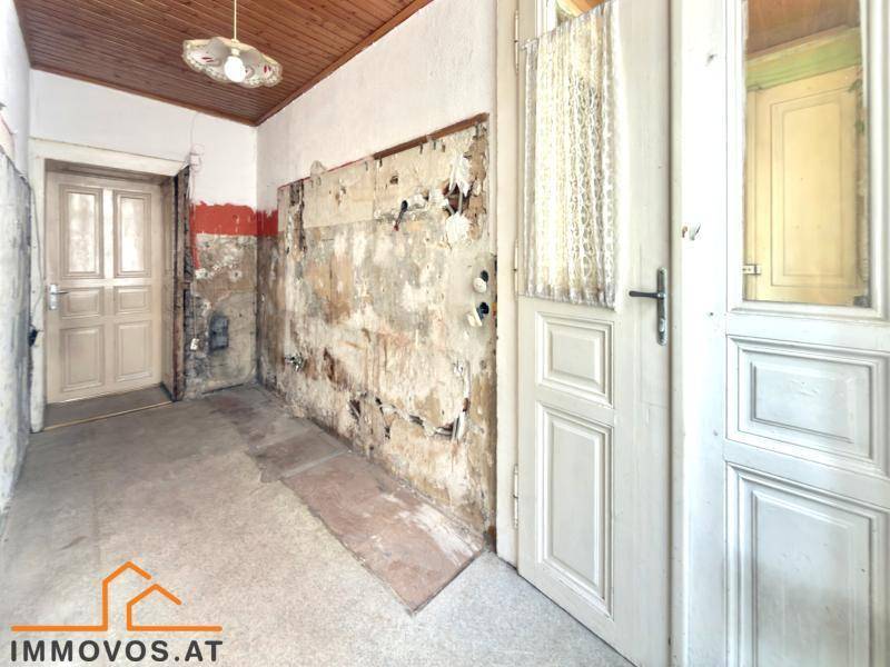 Gangbereich mit abblätternder Farbe an den Wänden und Holztäfelung an der Decke, der eine Renovierung benötigt.