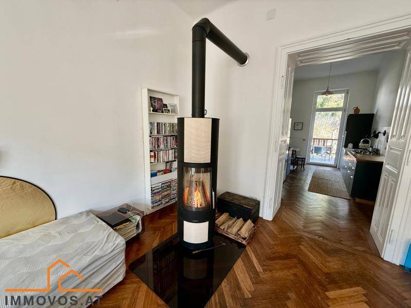 Moderner Kaminofen im Wohnzimmer mit Blick in die angrenzende Küche und Holzboden.