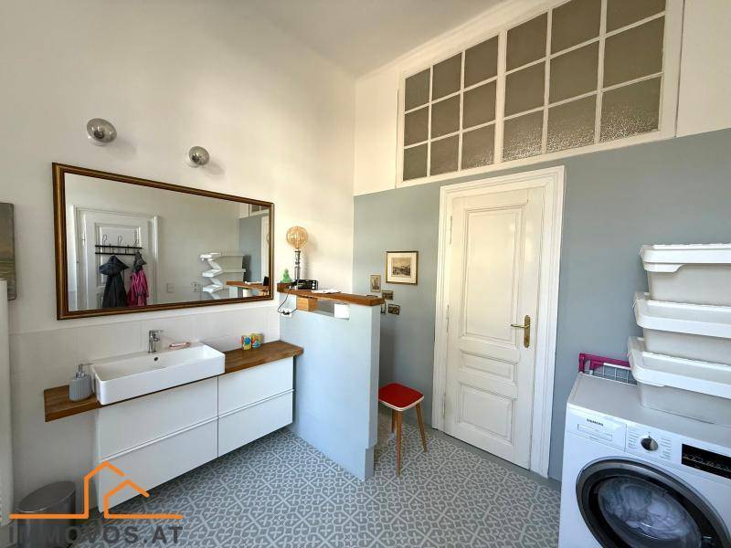 Geräumiges Badezimmer mit Waschmaschine, modernem Waschtisch und dekorativen Fliesen.