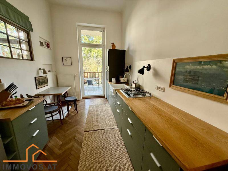 Schmale Küche mit Holz-Arbeitsplatten, Gasherd und Zugang zu einem kleinen Balkon.