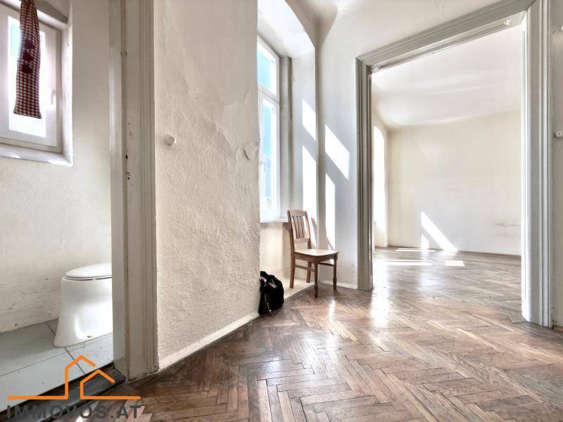 Kleiner WC-Bereich mit Fenster und angrenzendem Flur, der den Altbaucharme bewahrt.