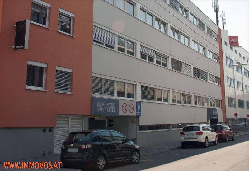 Außenansicht eines Bürogebäudes mit Parkplätzen und Zufahrt zur Tiefgarage.