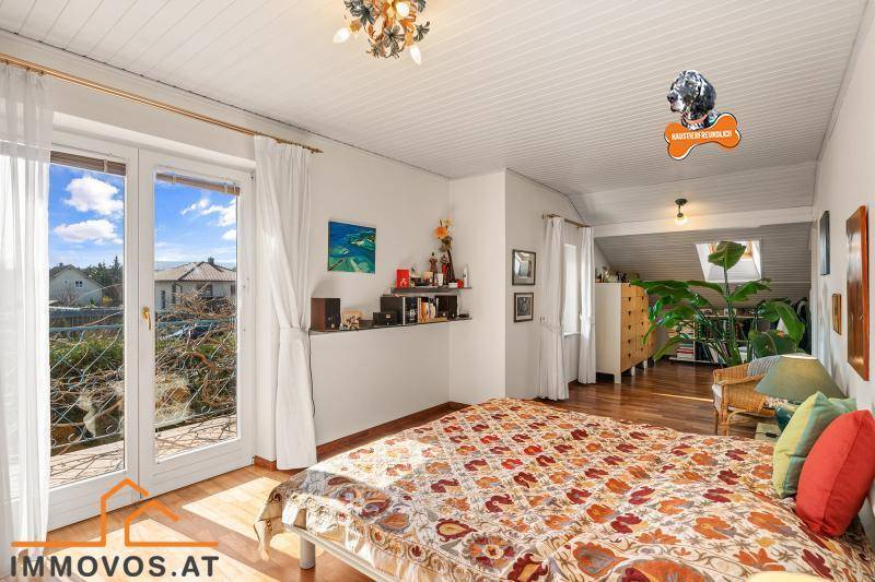 Helles Schlafzimmer mit Holzboden, Zugang zum Balkon und Blick auf die Umgebung.