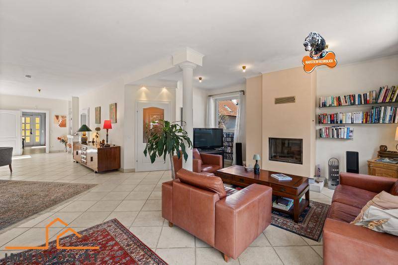 Geräumiges Wohnzimmer mit Kamin, bequemen Ledersofas und Fliesenboden, ideal zum Entspannen.