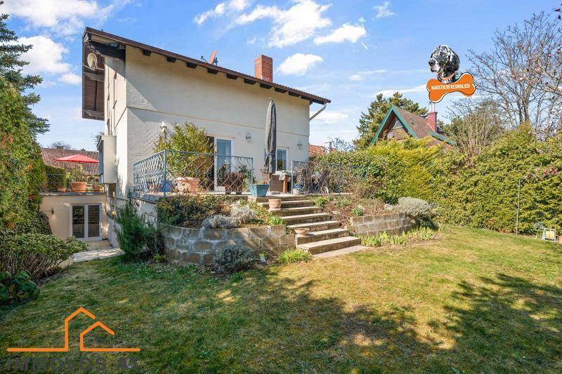 Großer Garten mit Rasenfläche, bepflanzten Beeten und einer erhöhten Terrasse am Haus.