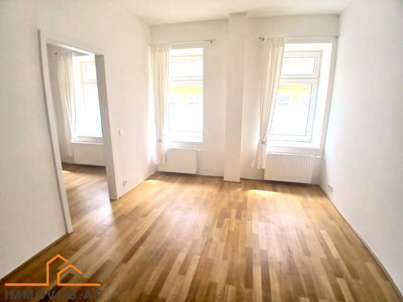 Lichtdurchfluteter Raum mit Parkettboden, zwei Fenstern und Heizkörpern, ideal für Wohn- oder Schlafzimmer.