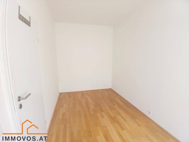 Schmaler Raum mit Parkettboden und weißer Tür, ideal als Flur oder kleines Arbeitszimmer.
