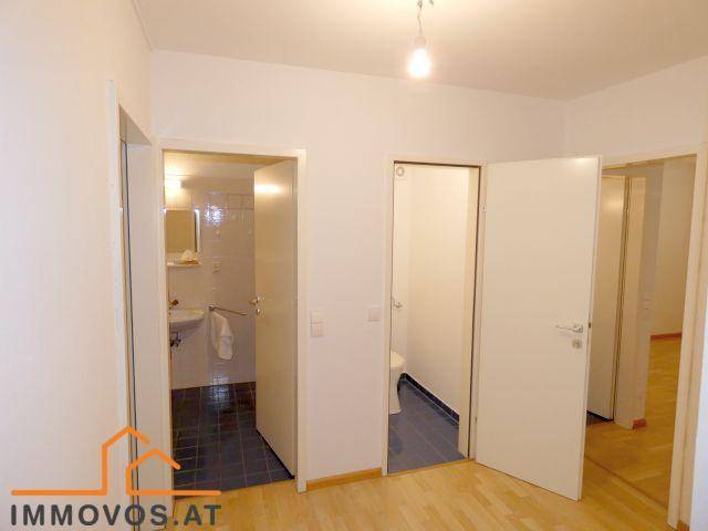 Flur mit offenen Türen zu einem Badezimmer und einer separaten Toilette, ausgestattet mit hellem Holzboden.