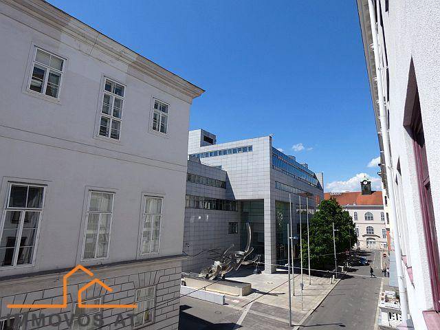 Blick auf eine städtische Straße mit traditionellen und modernen Gebäuden unter einem klaren blauen Himmel.
