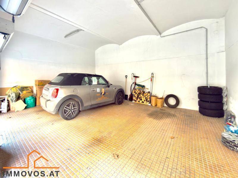 Geräumige Garage mit Platz für ein Fahrzeug, Lagerfläche und Reifen.