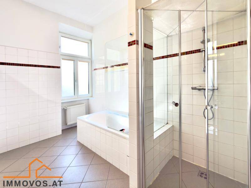 Helles Badezimmer mit Badewanne, Duschkabine und Fenster für natürliche Belüftung.