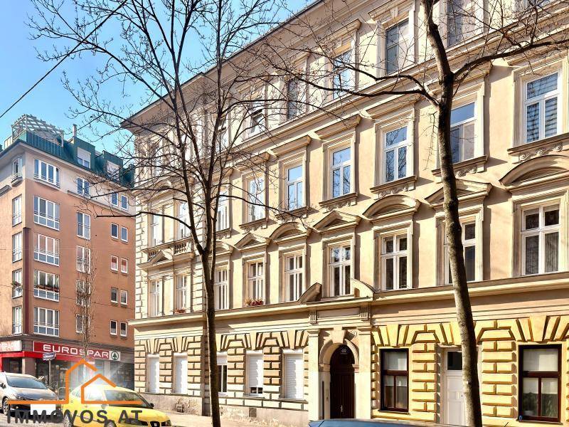 Attraktive Fassade eines Mehrfamilienhauses mit vielen Fenstern und Bäumen davor.