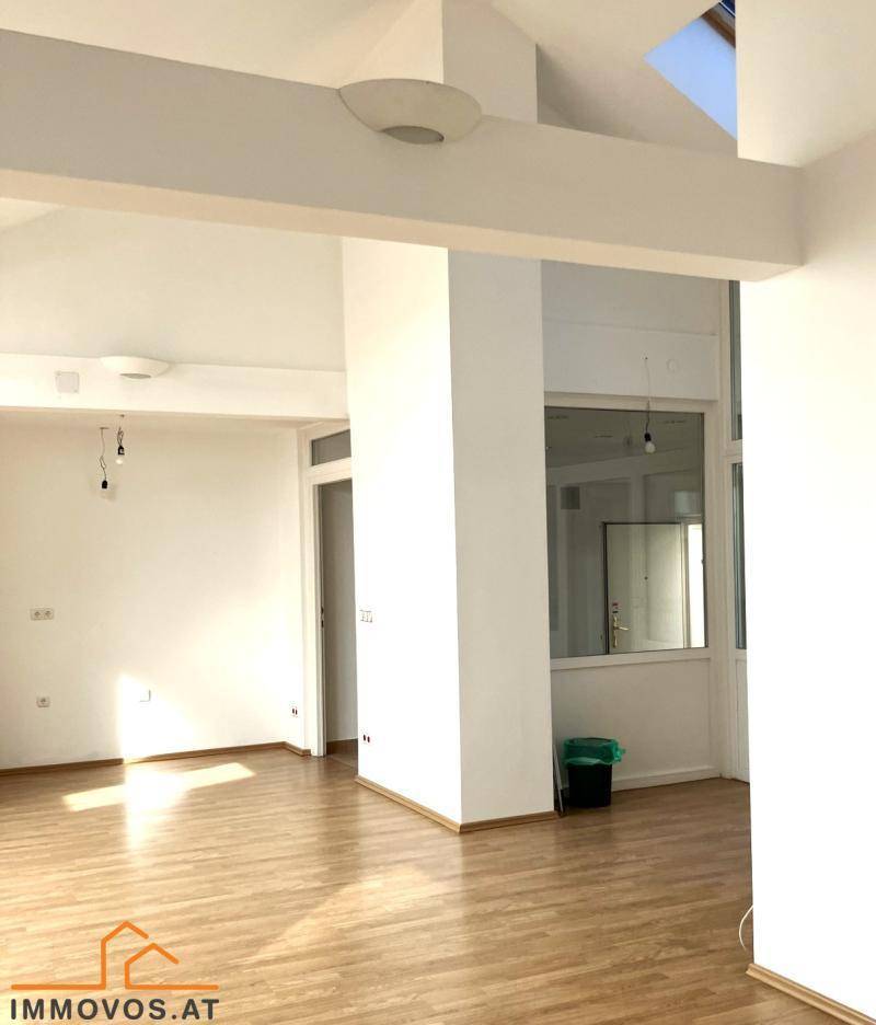 Heller, leerer Raum mit Holzboden, hohen Decken und einem Dachfenster, ideal für ein Wohnzimmer.