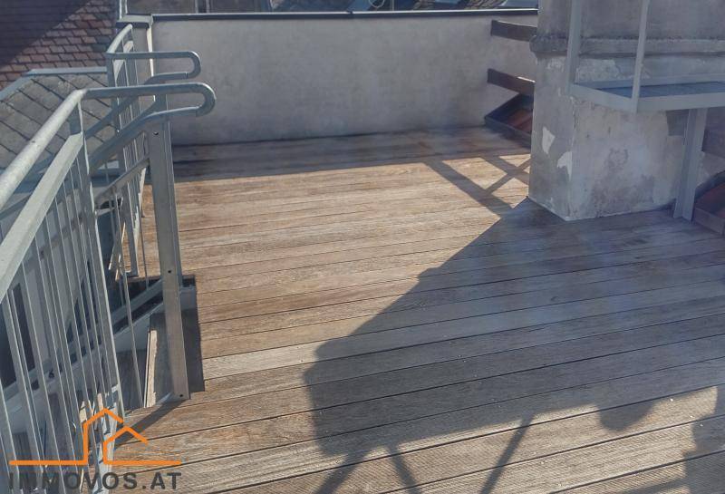 Geräumige Holzterrasse mit Metallgeländer und integriertem Grillbereich, ideal für Outdoor-Aktivitäten.
