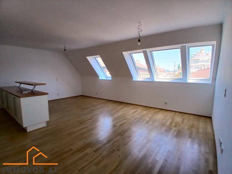 Geräumiger Dachbodenraum mit schrägen Wänden, Holzboden und mehreren Dachfenstern für viel Licht.