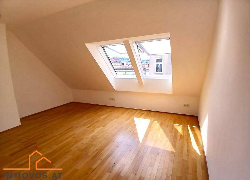 Heller Dachbodenraum mit Holzboden und einem großen Dachfenster, das viel Tageslicht hereinlässt.