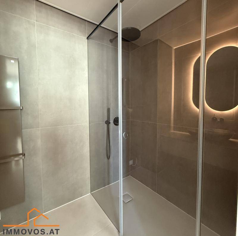 Elegante, begehbare Dusche mit Regenduschkopf und Glasabtrennung in einem modern gefliesten Badezimmer.