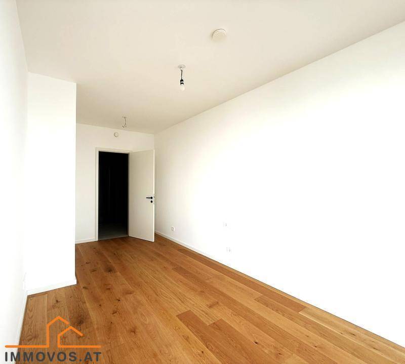 Schlichter, heller Raum mit Holzboden und weiß gestrichenen Wänden, ideal als Schlafzimmer oder Arbeitszimmer.