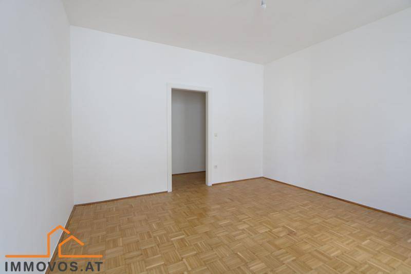 Leerer Raum mit Fischgrätparkettboden und weiß gestrichenen Wänden.