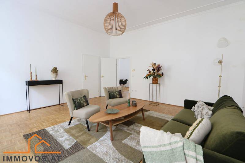 Stilvolles Wohnzimmer mit moderner Einrichtung, Holztisch und Fischgrätparkettboden.
