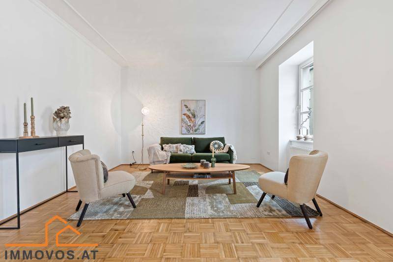 Gemütliches Wohnzimmer mit grünem Sofa, beigen Sesseln und Fischgrätparkettboden.