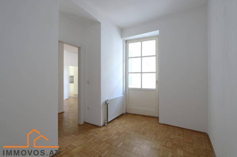 Kleiner Raum mit Fischgrätparkettboden und Zugang zu einem Balkon.